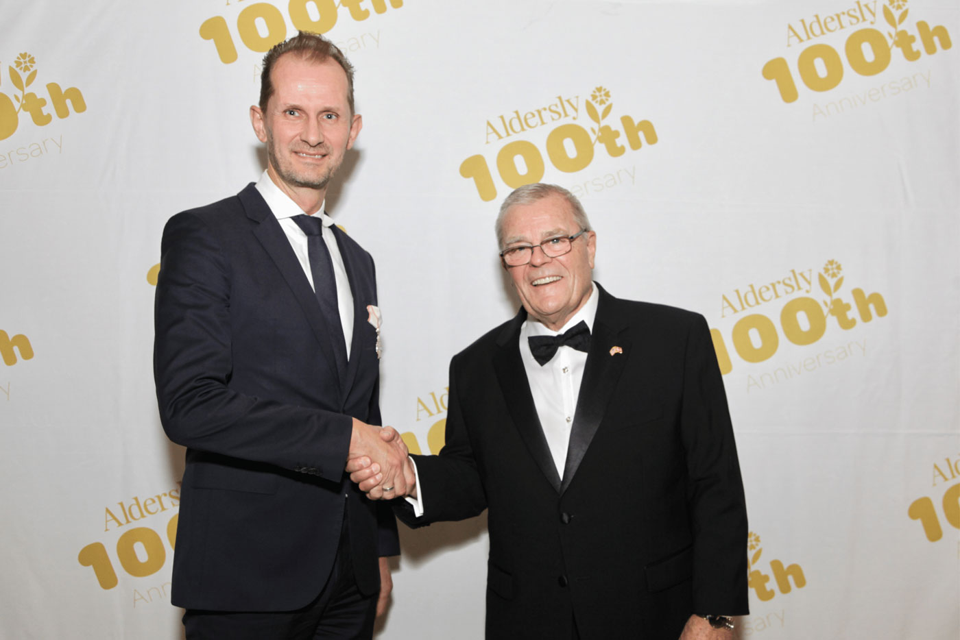 Two men shaking hands in tuxes